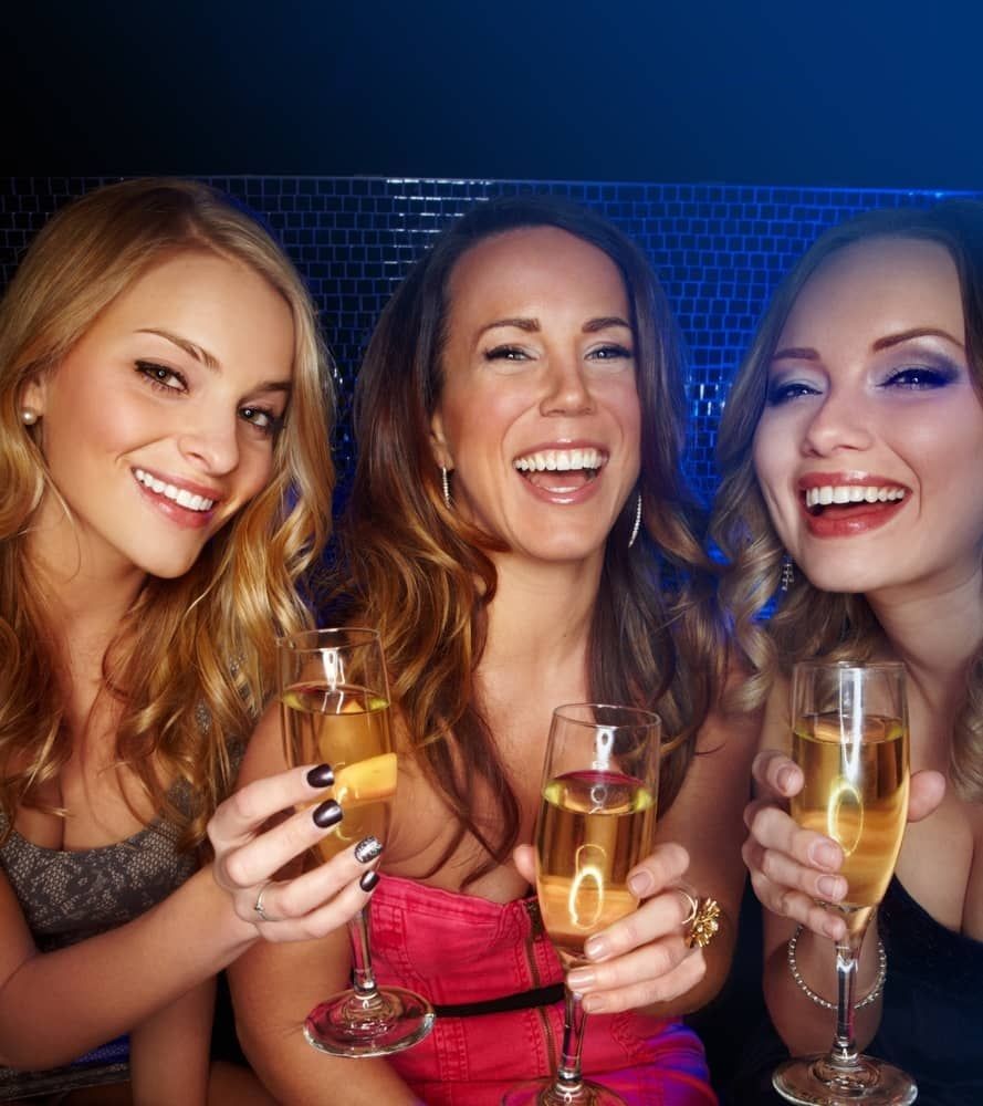 Three women enjoying drinks and laughing at a Las Vegas nightclub during a Crawl Group event